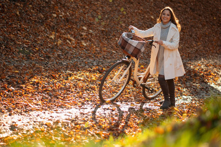 Beautiful woman with bicycle walking around the autumn leaves and having fun in park or forest. Relaxation, enjoying, solitude with nature conceptの写真素材