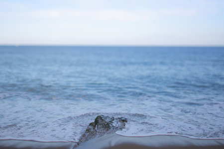 A serene view of the ocean with gentle waves lapping against the shore under a clear blue sky.