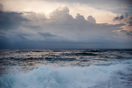 A stormy ocean scene with crashing waves and a cloudy sky, creating a dramatic and moody atmosphere....