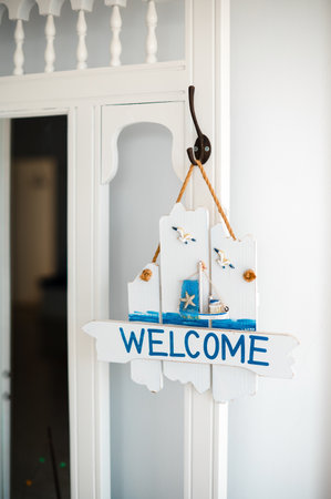 A nautical-themed welcome sign hangs on a white wall, featuring seagulls and a lighthouse design.の写真素材