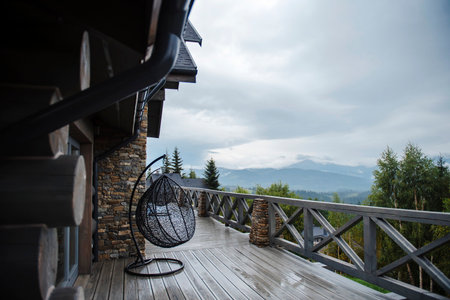 A wooden deck with a hanging chair and mountain view.の写真素材