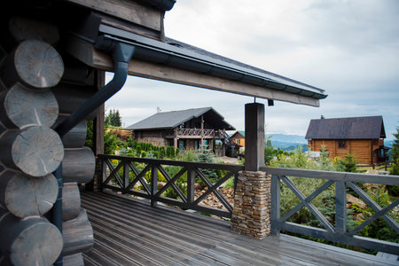 Rustic wooden cabins in a mountainous landscape with cloudy sky.