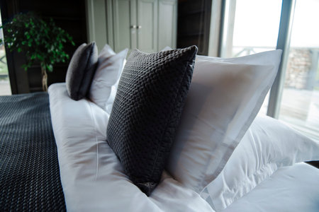Cozy bedroom with textured pillows and soft bedding near a window.の写真素材