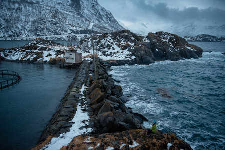 A rugged coastal landscape with snow-covered rocks and a small cabin.