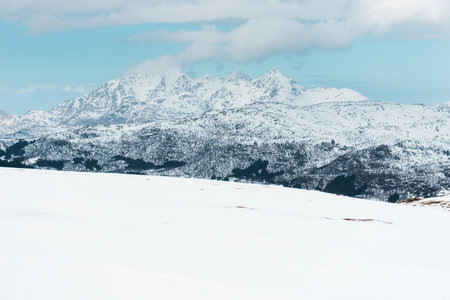Snow-covered mountain landscape with cloudy sky.の写真素材