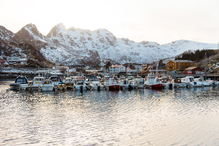 Scenic harbor with boats and snow-covered mountains in the background.の写真素材