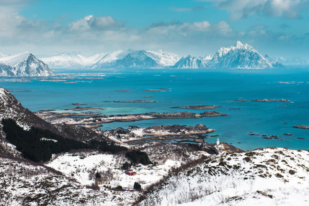 Scenic view of snowy mountains and islands in a blue sea under a cloudy sky.