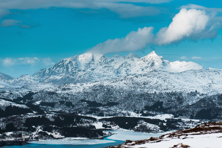 Snow-covered mountains under a blue sky with scattered clouds. Lofoten islands, Norwayの写真素材