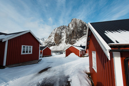 Red wooden cabins in a snowy landscape with mountains. Lofoten islands, Norwayの写真素材
