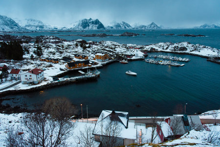 Scenic view of a snowy coastal village with mountains and boats. Lofoten islands, Norway