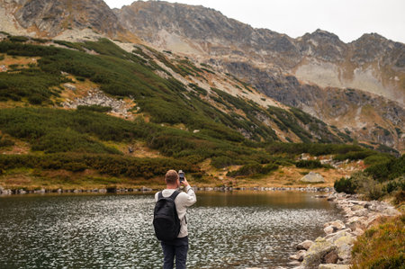 Hiker man taking a photo of a Tatry mountains landscape by a lake. Zakopane, Polandの写真素材