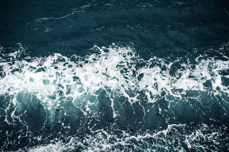 Aerial view of ocean waves crashing on the surface, creating white foam.の写真素材