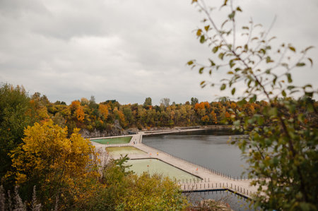 Scenic view of a lake surrounded by autumn trees and a wooden walkway.の写真素材