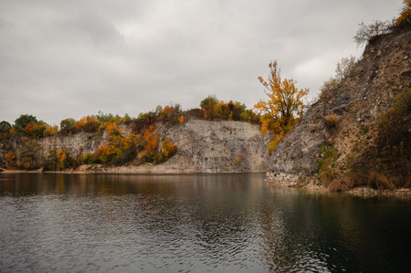 Autumn landscape with rocky cliffs and calm lake under cloudy sky. Zakrzowek, Krakow