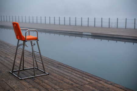 Empty lifeguard chair by a foggy swimming pool.の写真素材