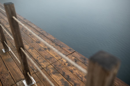 Wooden dock with rope railing over calm water. Zakrzowek, Krakow