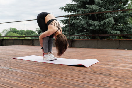 Strong sporty woman with short hair practicing yoga on a wooden deck outdoors.の写真素材