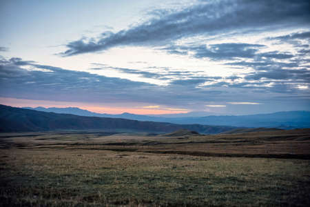 Grassland under mountains at sunriseの写真素材