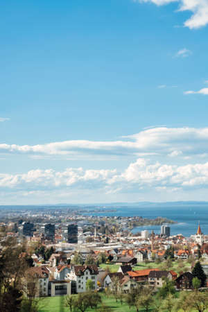 Grass and buildings under blue sky and white cloudsの写真素材