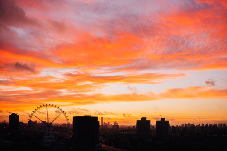 Ferris wheel under burning cloud sky at sunsetの写真素材