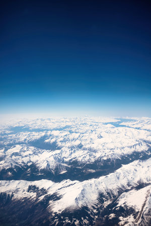 Aerial view of snow covered mountain range with blue sky background.の写真素材
