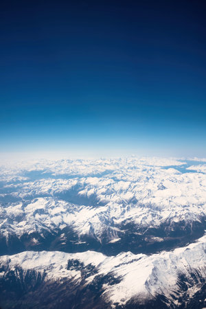 Aerial view of snow covered mountain peaks with clear blue sky.の写真素材