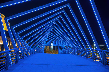 Pedestrian bridge with blue lights in the city at night.