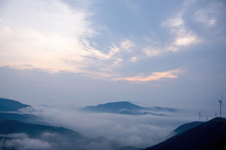Beautiful landscape of windmill on the mountain with fog in the morningの写真素材