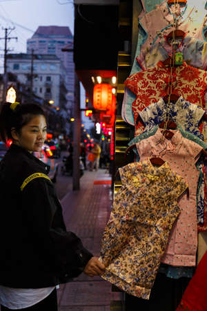 A tourist looking at Qipao, a traditional Chinese Dress bring sold on Nanjing Roadのeditorial素材