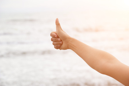 Hand with thumb up like  on the seaの写真素材