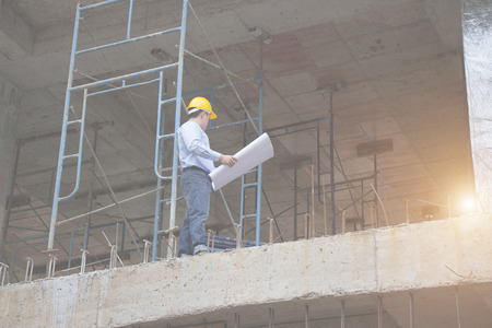 Engineer and Architect working at Construction Site with blueprint
