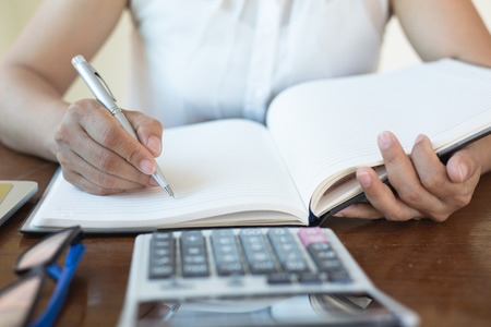 Hand women Writing tax on desk about at home office.business concept