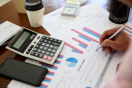 Close up Businessman holding pen at financial on wooden desk in home office. analytic research concept.の写真素材