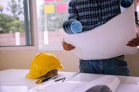 architect man reading with blueprint to build houses. After agreeing the employment price the cost...