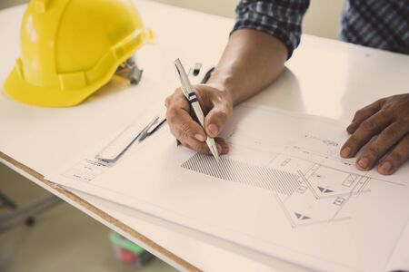 architect man handwriting with blueprint to build houses. After agreeing the employment price the cost of construction and repair real estateの写真素材