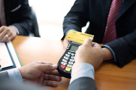 Close up of hands businessman use a credit card swipe to pay for the share transfer fees in the...