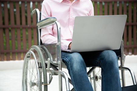 Disabled man is wheelchair finding information on notebooks at home.Disabled concept