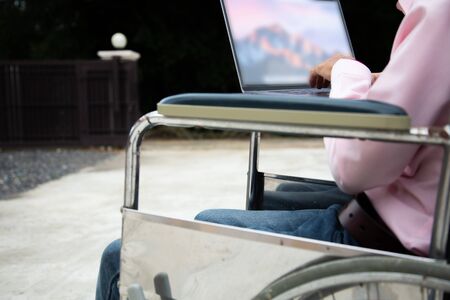 Disabled man is wheelchair finding information on notebooks at home.Disabled concept
