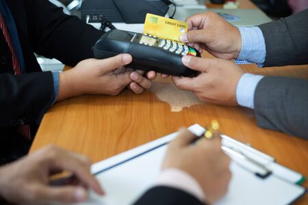 Close up of hands businessman use a credit card swipe to pay for the share transfer fees in the...