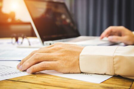 business man hands searching for data on Notebook with analyzing charts at his workplace.の写真素材