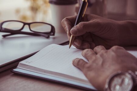 Close up Businessman holding pen at financial on wooden desk in home office. analytic research...