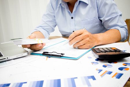 businessman using calculator and holding money for calculate tax in office.