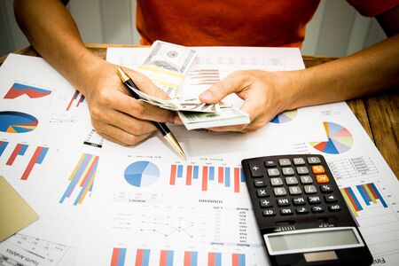 A businessman using calculator and holding money for calculate tax in office.の写真素材