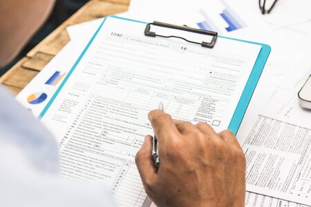 Hand business Writing tax on desk about at home officeの写真素材