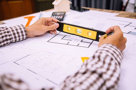 Close-up hand of male Architect drawing blueprint on work space in construction site.