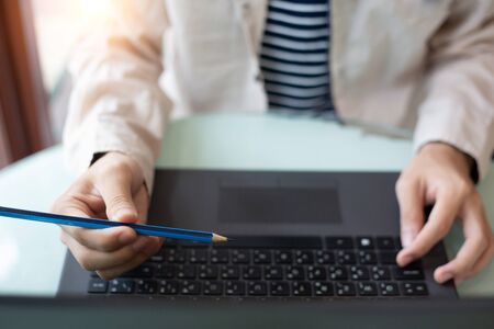 businessman hands searching for data on Notebook with analyzing charts at his workplace.