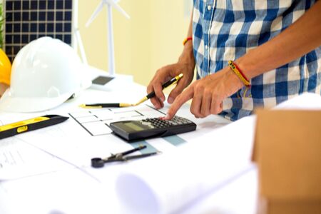 Architect calculating budge Construction project with blueprint  at Construction Site.concept