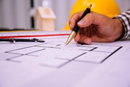 Close-up hand of male Architect drawing blueprint on work space in construction site.