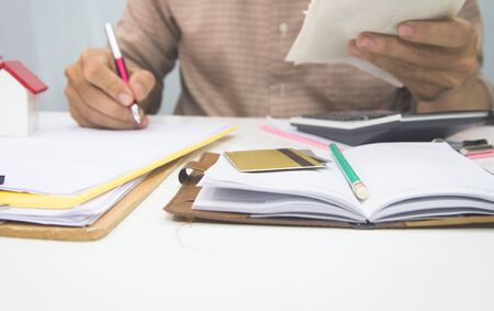 businessman using calculator and holding pen on tax paper in office.Accountingconcept.