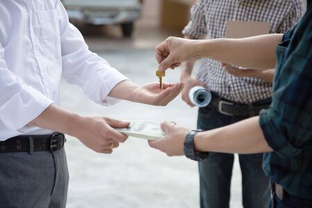 Engineers are giving the house keys to the architects to use to explore the inside of the house.の写真素材